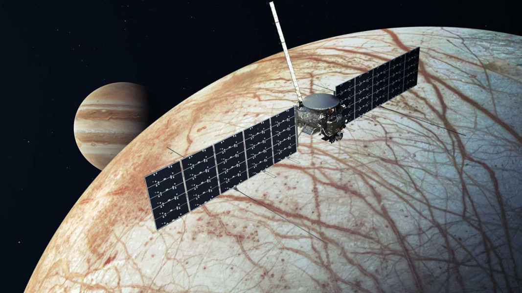 A spacecraft flying above Europa with Jupiter far in the background.
